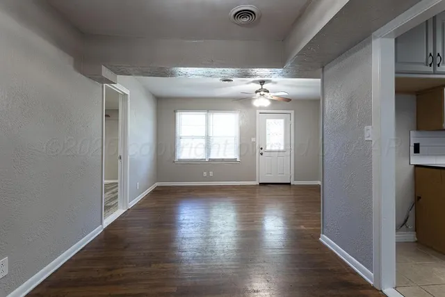 an empty room with wooden floor and windows