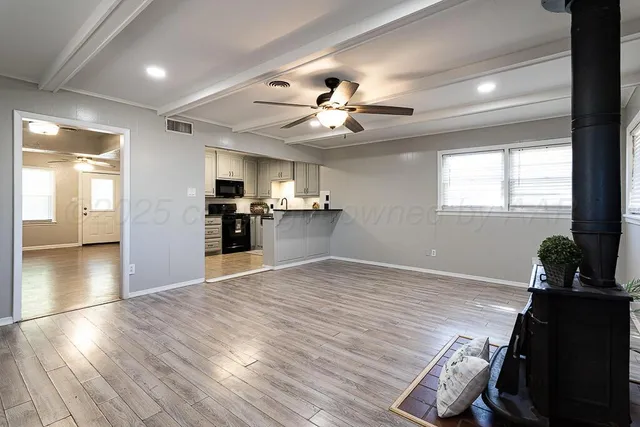 a view of an empty room with kitchen and window