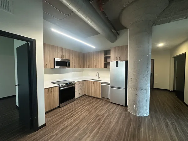 a large kitchen with a center island wooden floor and stainless steel appliances