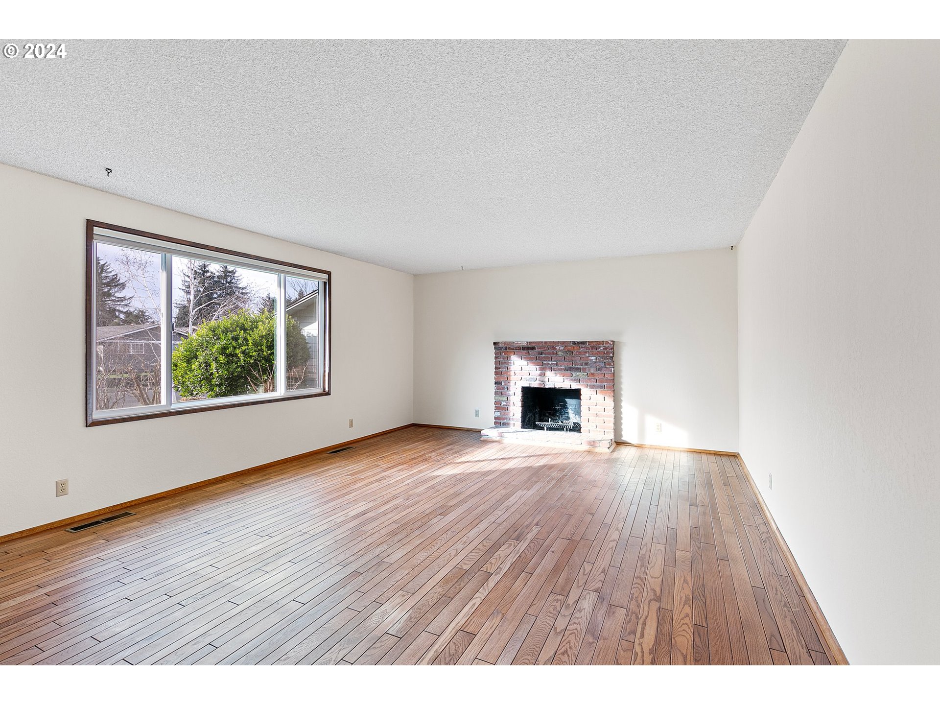 609 Rowan Avenue Springfield, OR 97477 - Photo 4 of 32 a view of an empty room with wooden floor and a window