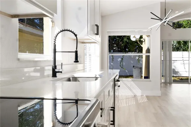 a kitchen with a window a sink and a dining table with wooden floor