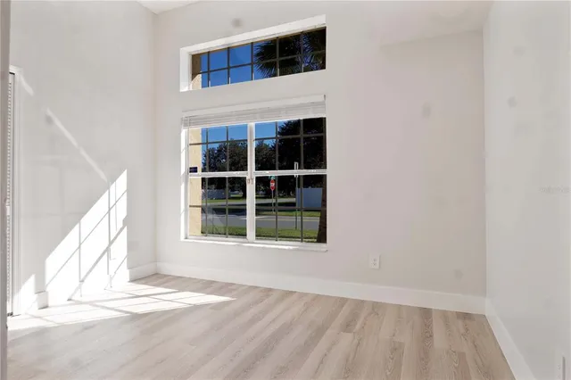 a view of an empty room with a window and wooden floor