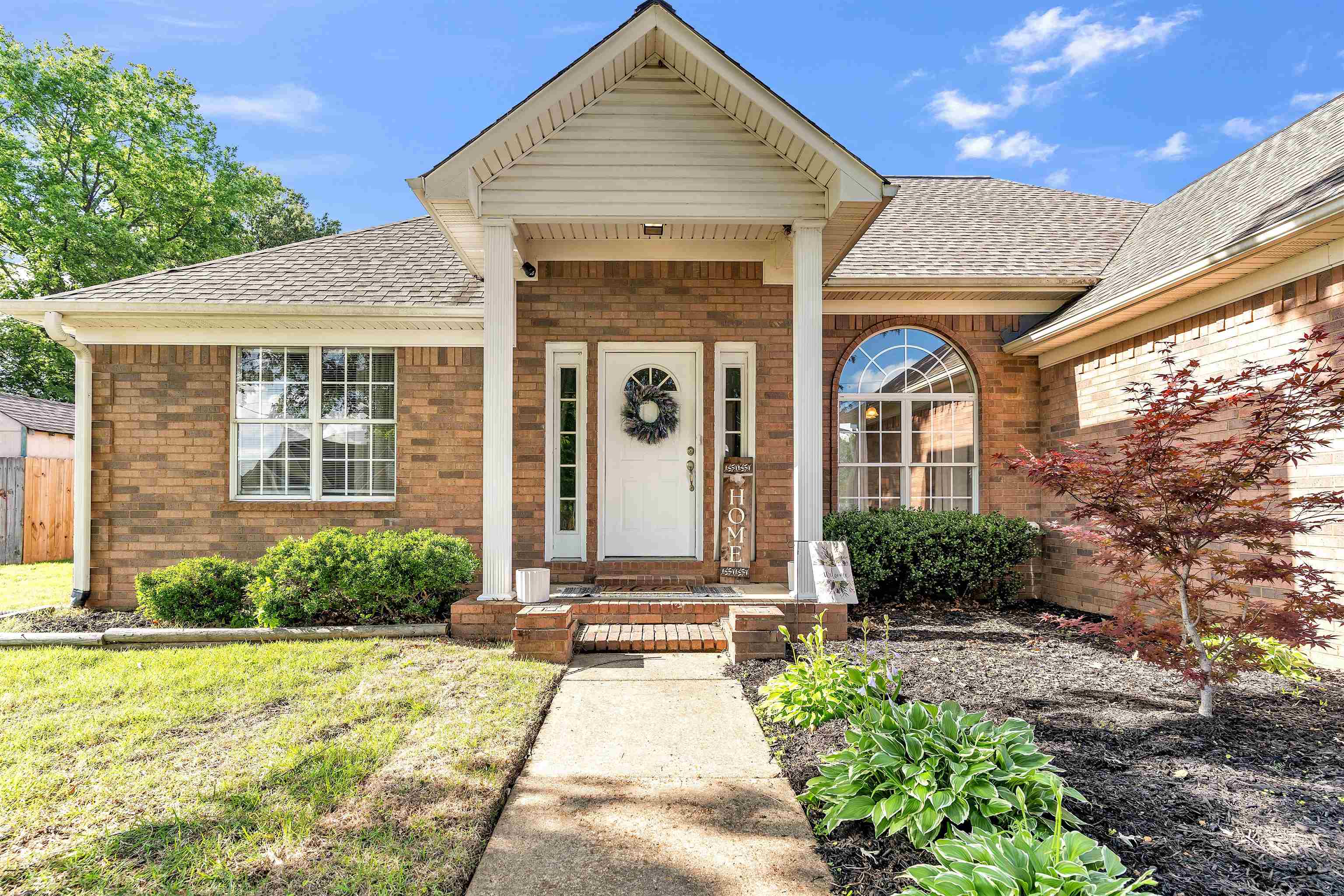 Doorway to property with roof with shingles, brick siding, and a porch