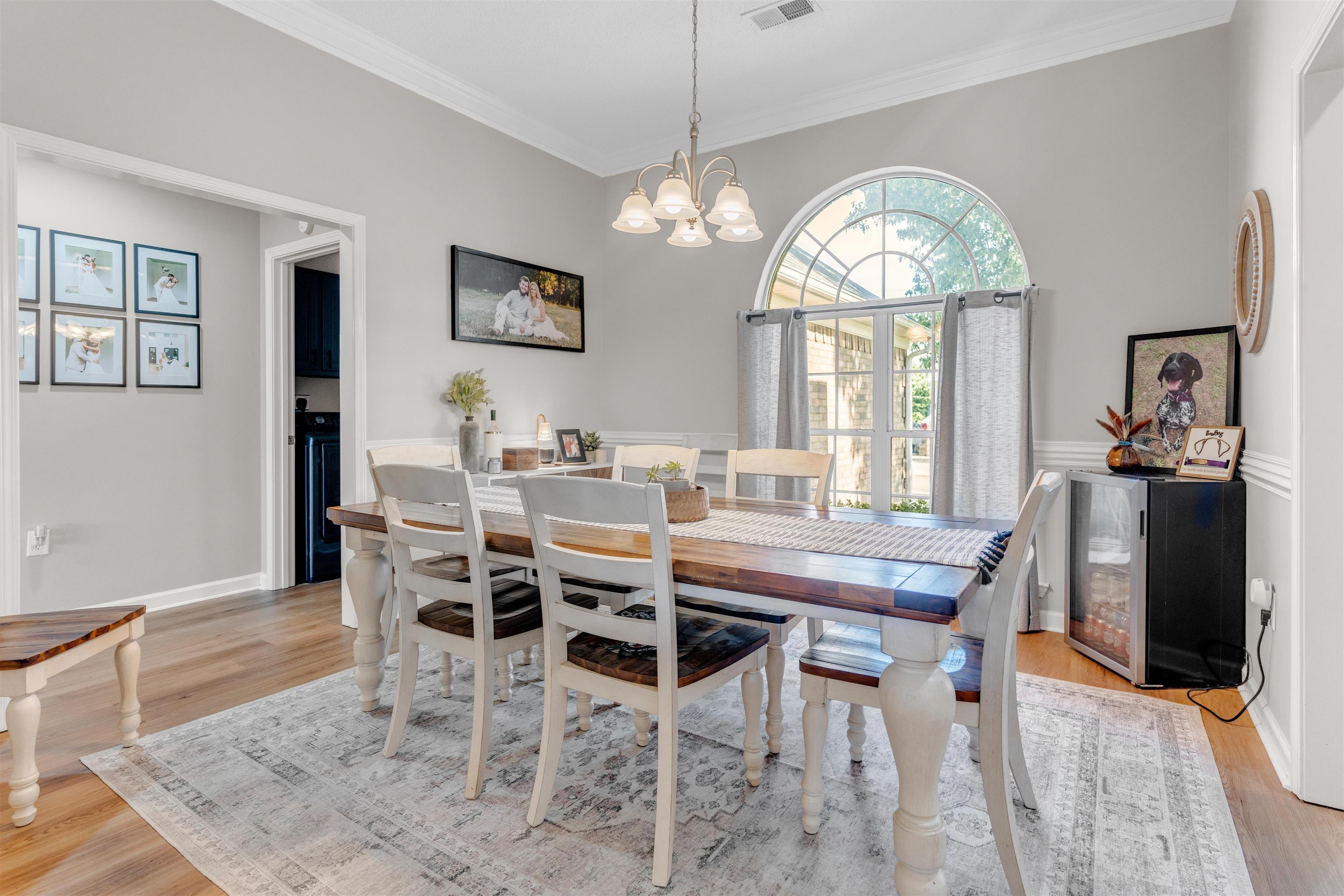 Dining area with ornamental molding, light wood-style floors, and a chandelier