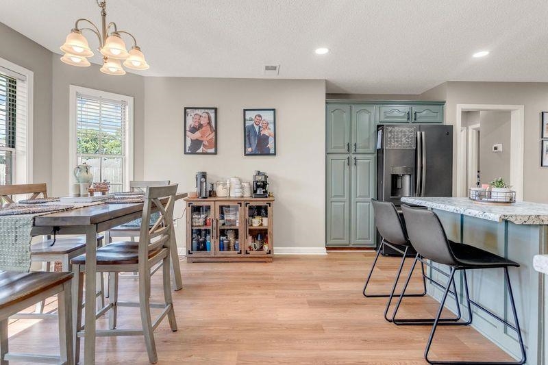 Dining space with a chandelier, light wood-type flooring, a textured ceiling, baseboards, and recessed lighting