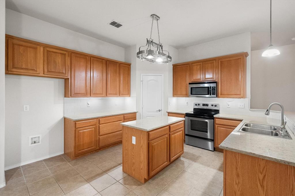 10929 Soft Shell Drive Venus, TX 76084 - Photo 22 of 39 a kitchen with stainless steel appliances granite countertop a sink dishwasher stove and refrigerator with wooden cabinets