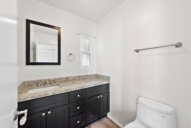 a bathroom with a granite countertop sink a toilet and mirror
