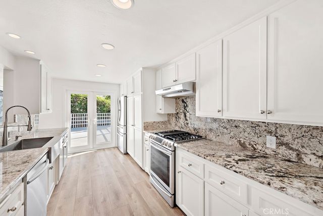 a kitchen with granite countertop a sink stove and cabinets