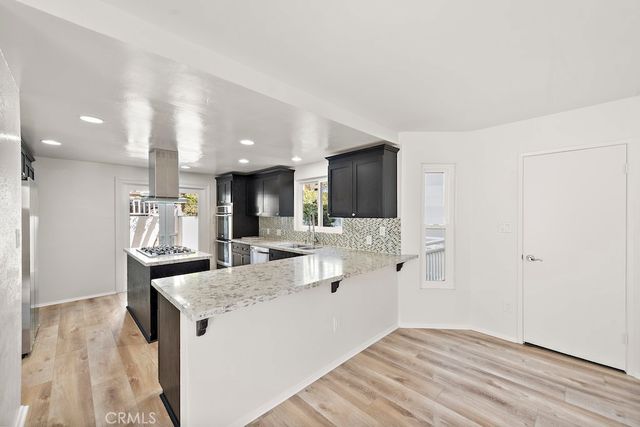 a kitchen with stainless steel appliances kitchen island granite countertop a refrigerator and a sink