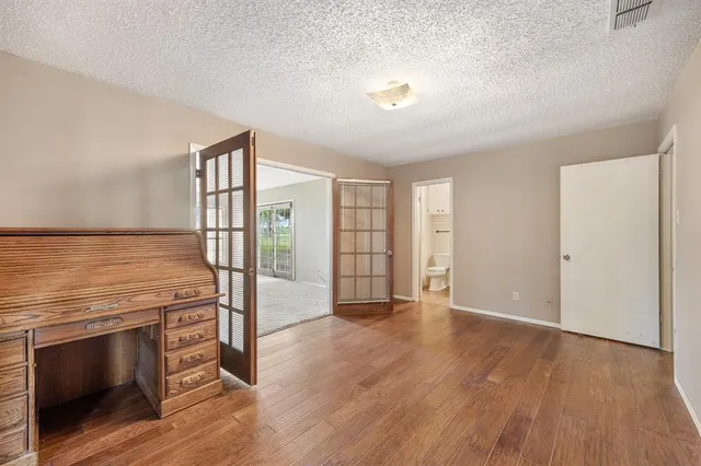 an empty room with wooden floor sink and windows