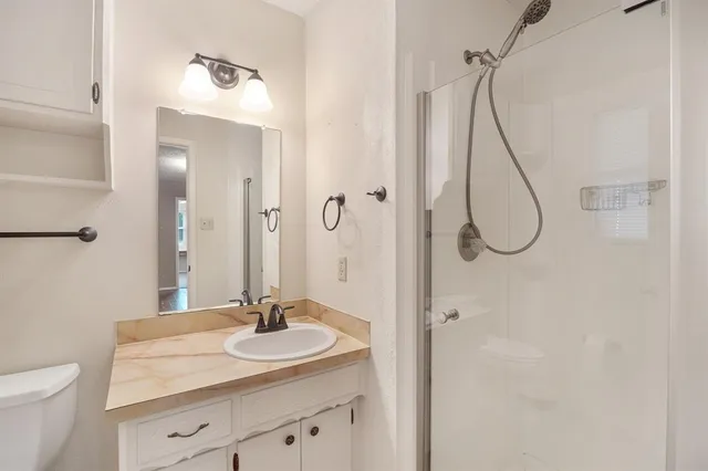 a bathroom with a granite countertop sink a toilet and a mirror