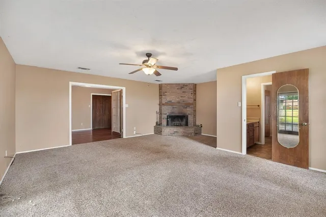 a view of an empty room with a fireplace and a chandelier fan