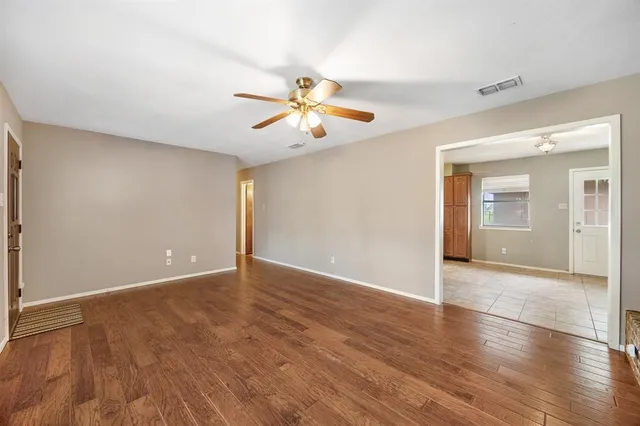 a view of an empty room with window and wooden floor