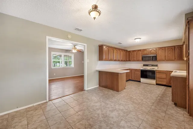 a kitchen with kitchen island a stove a sink a refrigerator and cabinets