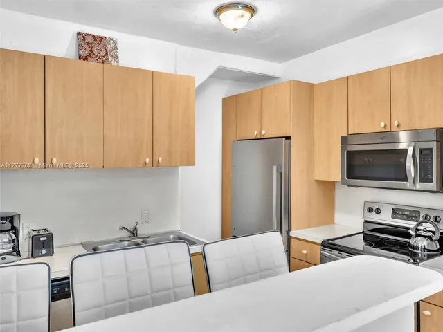 a living room with stainless steel appliances furniture windows and a kitchen view