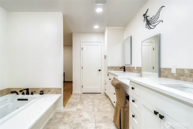 a bathroom with a tub sink and mirror