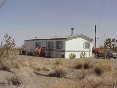 11625 Amarillo Road Pinon Hills, CA 92371 - Photo 1 of 1 a white house covered with tall trees