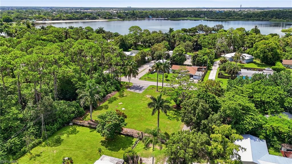 3417 Guilford Road Naples, FL 34112 - Photo 15 of 18 Expansive green lot with established foliage, surrounded by a lake and dense tree cover