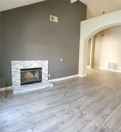 a view of an empty room with wooden floor fireplace and a window
