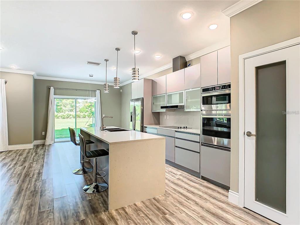 2000 Greenbriar Terrace Davenport, FL 33837 - Photo 3 of 50 a kitchen with stainless steel appliances kitchen island granite countertop a refrigerator a stove a sink and white cabinets with wooden floor