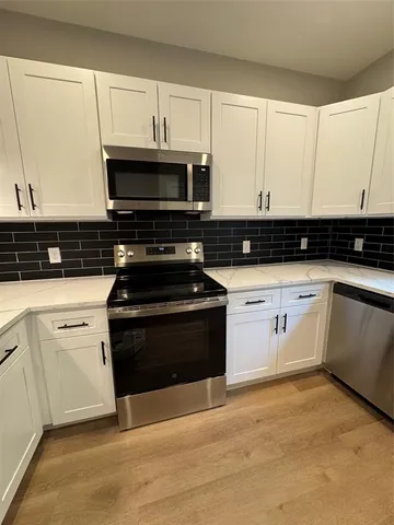 a kitchen with granite countertop white cabinets and black appliances