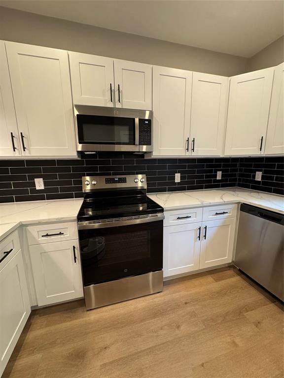 1505 Park Street, Unit A Commerce, TX 75428 - Photo 9 of 25 a kitchen with granite countertop white cabinets and black appliances