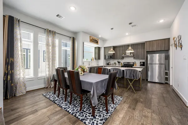 a kitchen with stainless steel appliances kitchen island granite countertop a dining table chairs refrigerator and sink