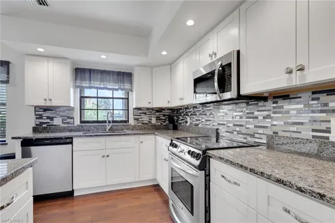 a kitchen with granite countertop white cabinets stainless steel appliances a sink and dishwasher