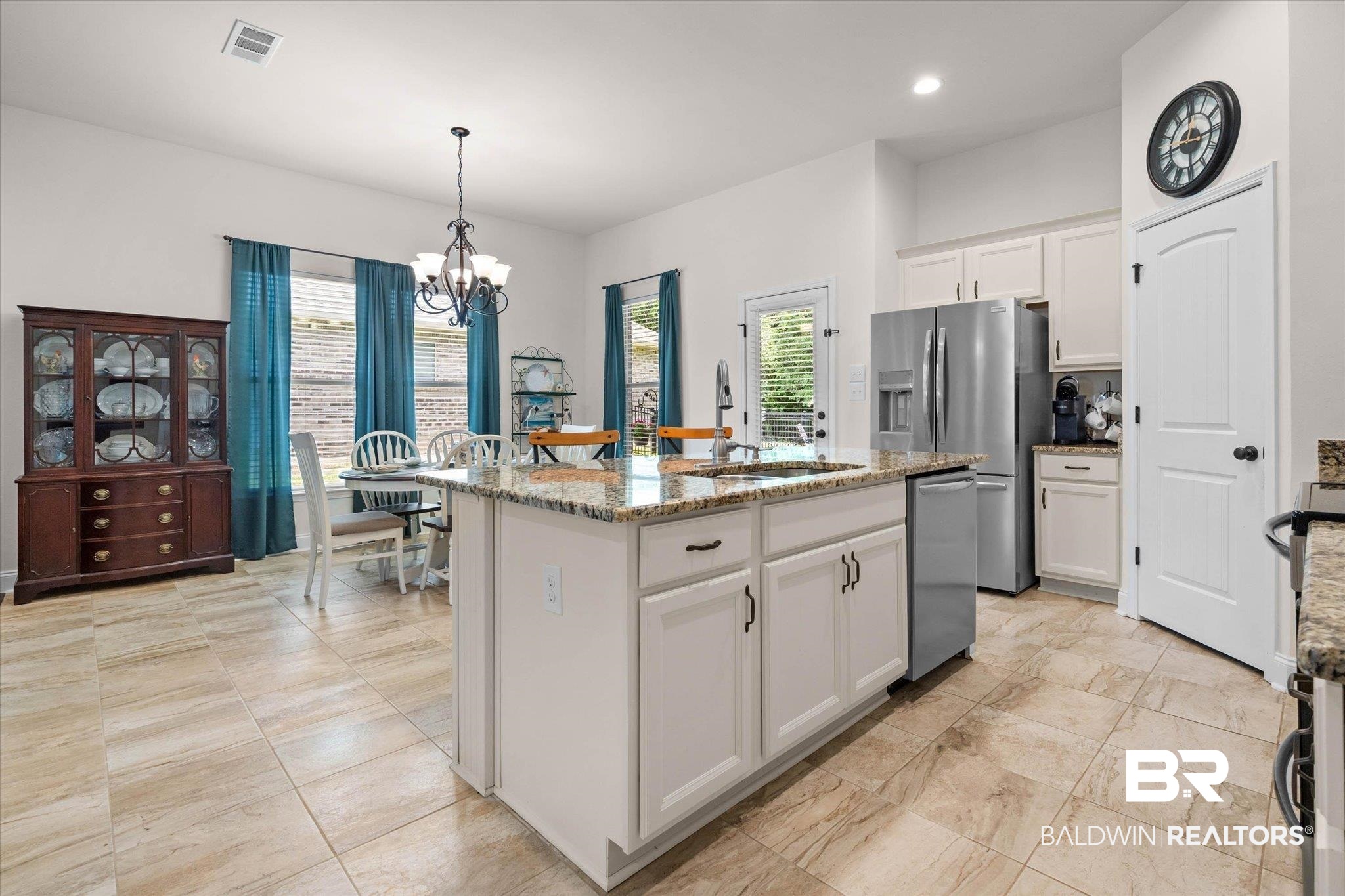 1270 Surrey Loop Foley, AL 36535 - Photo 8 of 27 Spacious kitchen featuring an expansive center island with an undermount sink, granite countertops, tile flooring, white cabinetry with dark hardware, and stainless steel appliances