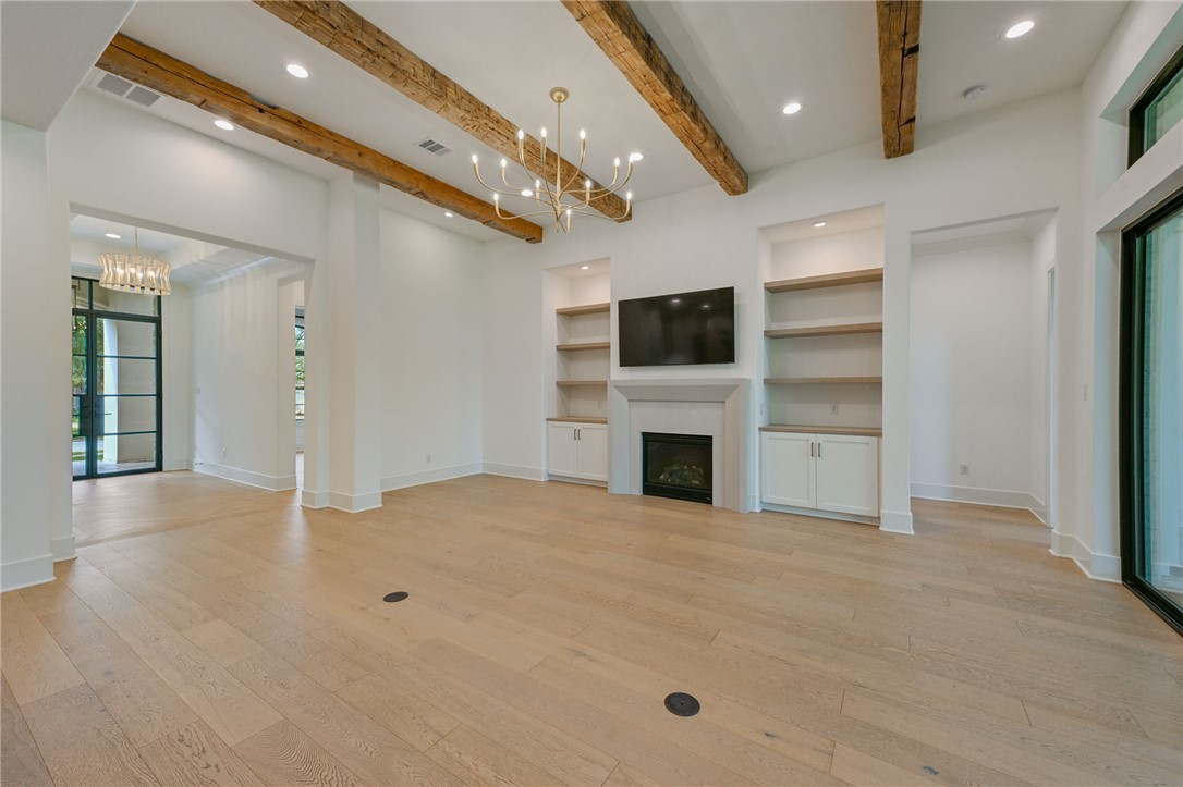 5115 Inverness Drive Bryan, TX 77802 - Photo 3 of 28 Spacious living area featuring exposed ceiling beams, light wood-finish flooring, and a fireplace with a stone surround