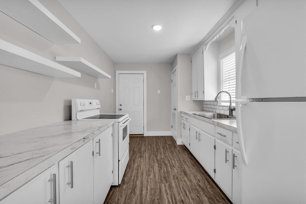 1908 South 19th Street Waco, TX 76706 - Photo 9 of 29 a large kitchen with granite countertop a stove top oven a sink a counter space and cabinets