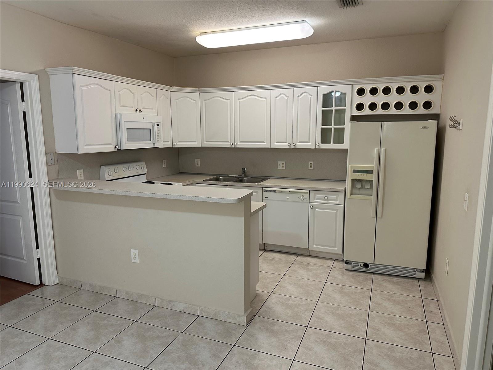 7549 Northwest 175th Street, Unit 7549 Hialeah, FL 33015 - Photo 13 of 34 a kitchen with a sink a refrigerator and cabinets