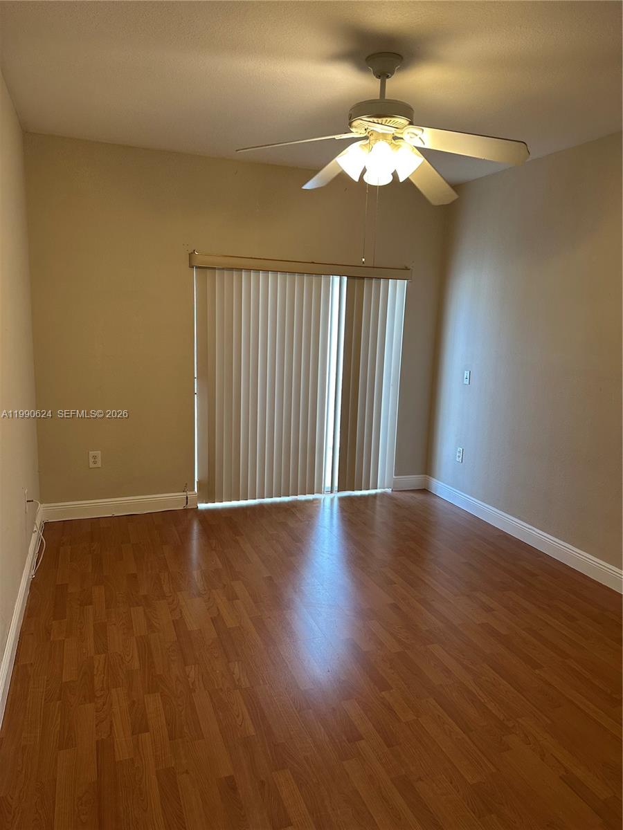 7549 Northwest 175th Street, Unit 7549 Hialeah, FL 33015 - Photo 20 of 34 an empty room with wooden floor fan and window