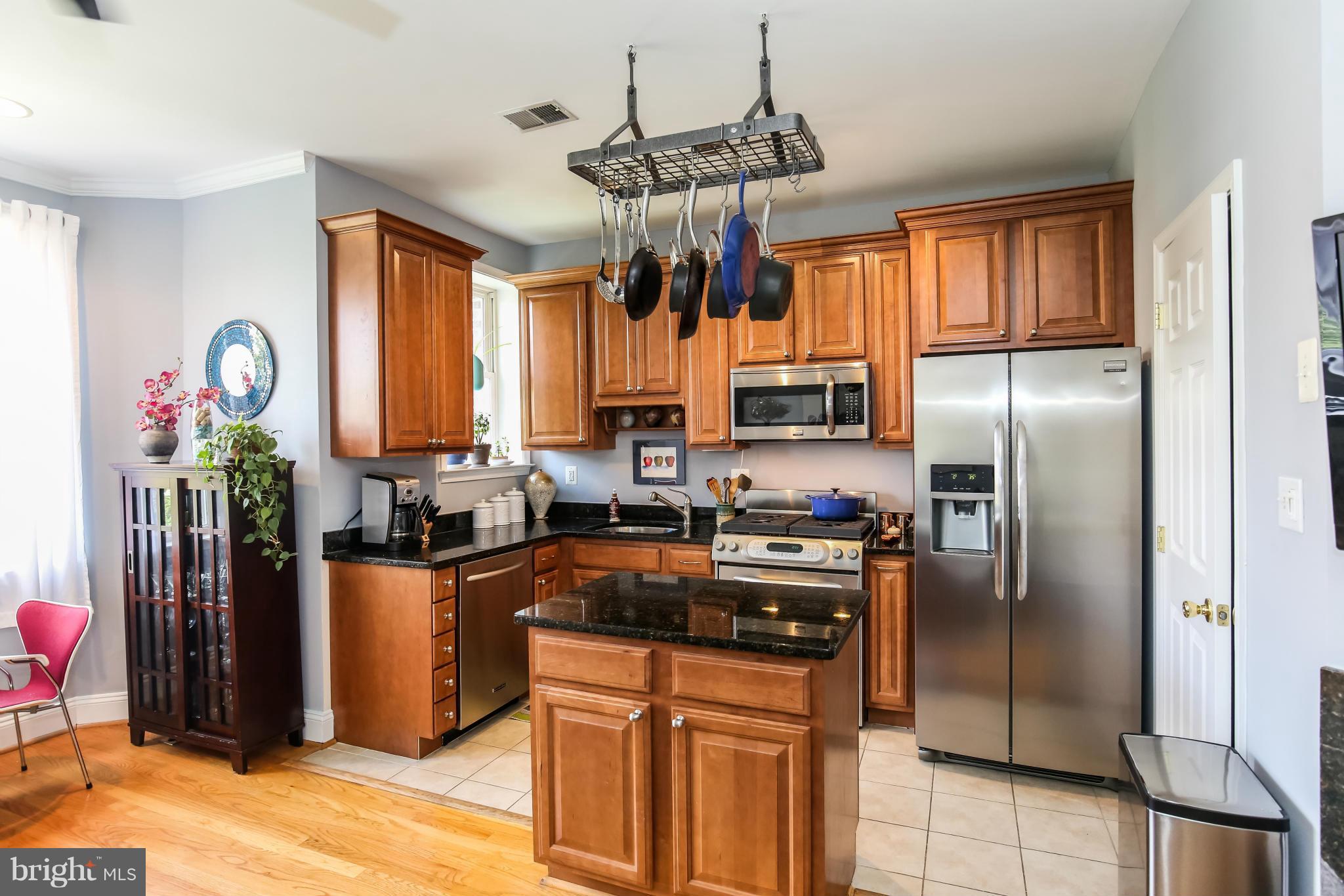1438 Columbia Road Northwest, Unit 402 Washington, DC 20009 - Photo 8 of 12 a kitchen with granite countertop a refrigerator cabinets stainless steel appliances and a chandelier