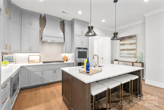 a kitchen with stainless steel appliances kitchen island granite countertop a sink a stove a dining table and chairs