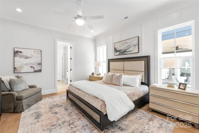 a bedroom with a large bed couch and two windows