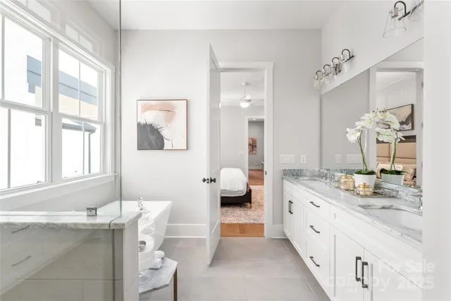a spacious bathroom with a granite countertop double vanity sink a mirror and a bathtub