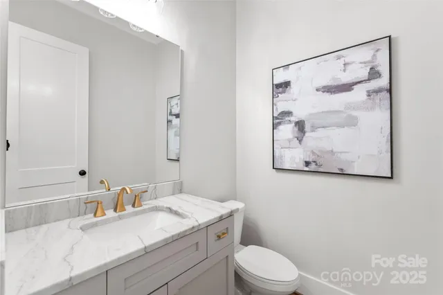 a bathroom with a granite countertop sink mirror vanity and toilet