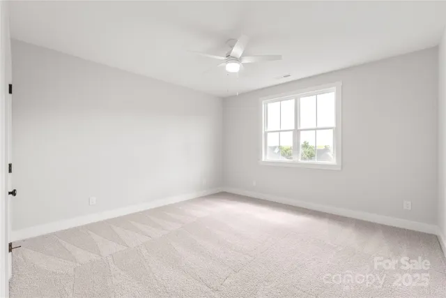 an empty room with windows and chandelier fan