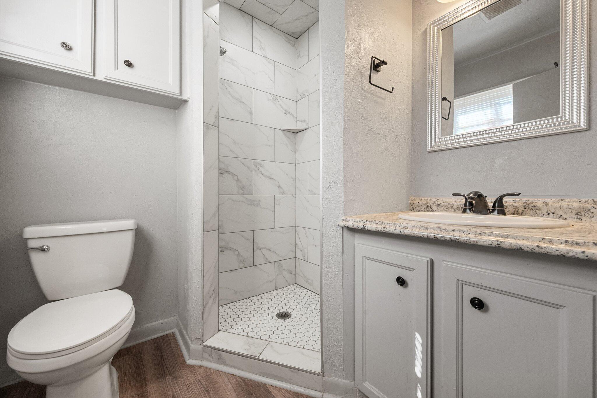 2319 53rd Street Lubbock, TX 79412 - Photo 11 of 20 a bathroom with a granite countertop toilet sink and mirror