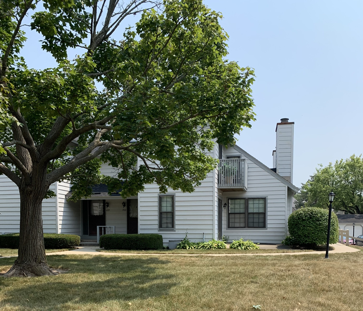 a view of a house with a yard and large tree