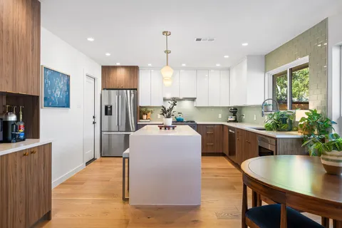 a kitchen with kitchen island a counter top space a sink stainless steel appliances and cabinets