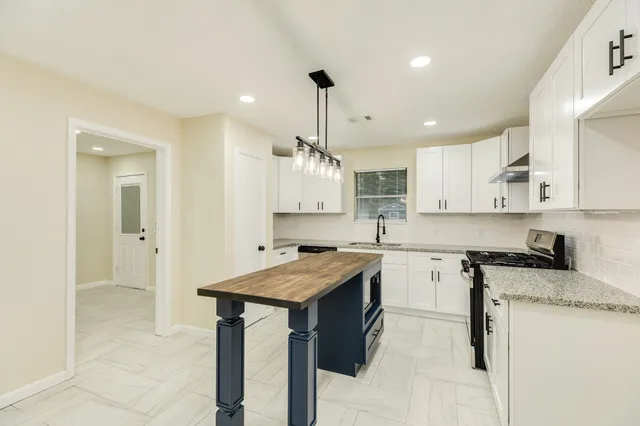 a kitchen with a stove a sink dishwasher and a refrigerator with wooden floor