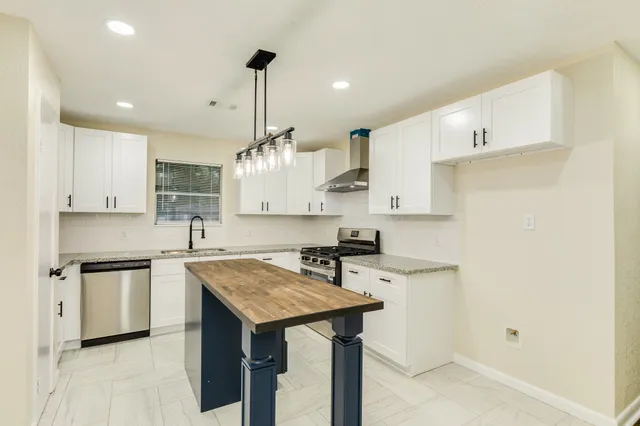 a kitchen with a sink a center island stainless steel appliances and cabinets