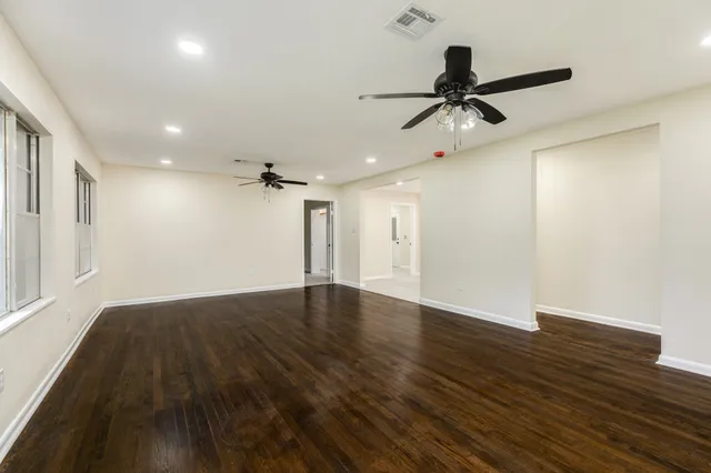 a view of empty room with wooden floor and fan