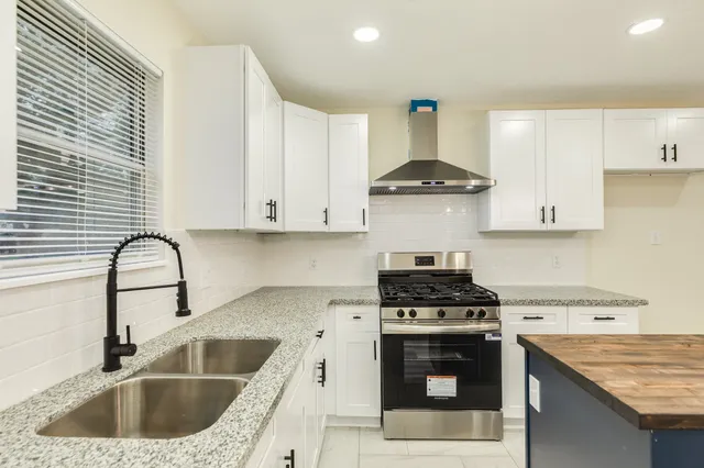 a kitchen with granite countertop a stove top oven sink and cabinets