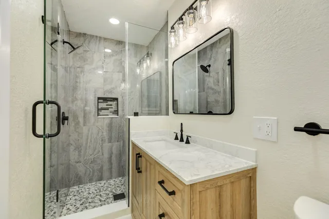 a bathroom with a sink vanity mirror and shower