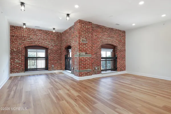 a view of an empty room with wooden floor and a fireplace