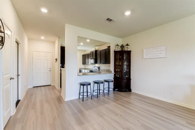 a room with stainless steel appliances a dining table wooden floor and a refrigerator