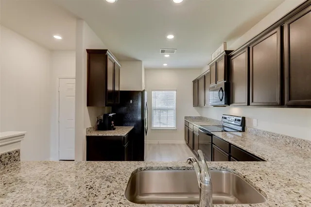 a kitchen with stainless steel appliances granite countertop a sink stove and refrigerator